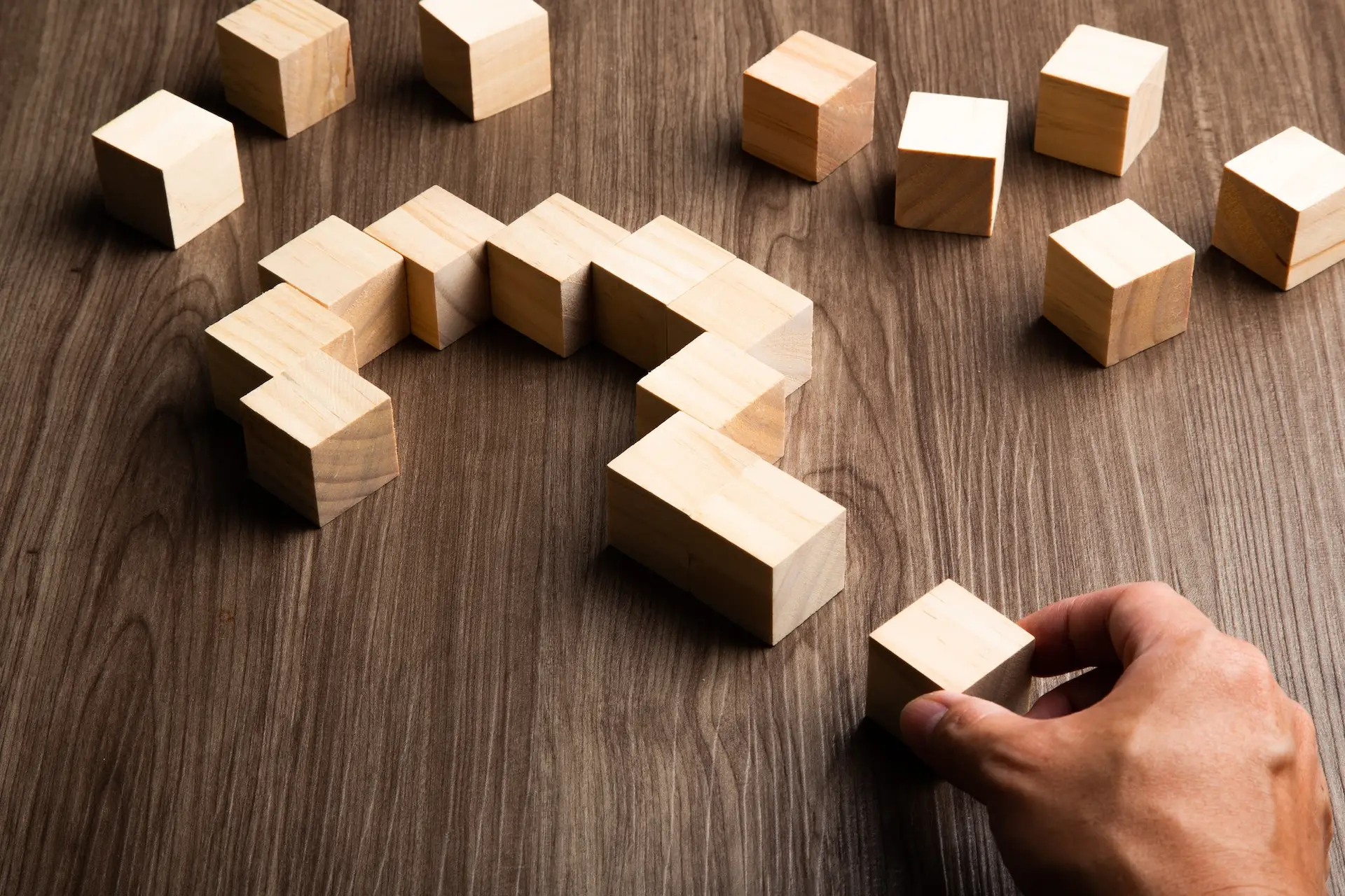 Hand forming bigger question mark. question mark on wooden table background